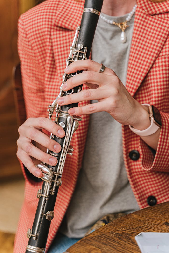 Close-up of a musician playing a clarinet with focus on hands and instrument.